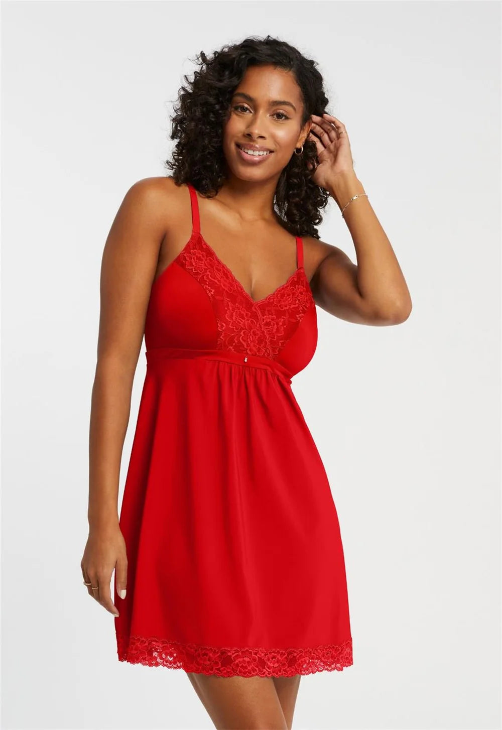 A woman modeling a red lace and satin slip dress against a light gray studio background.