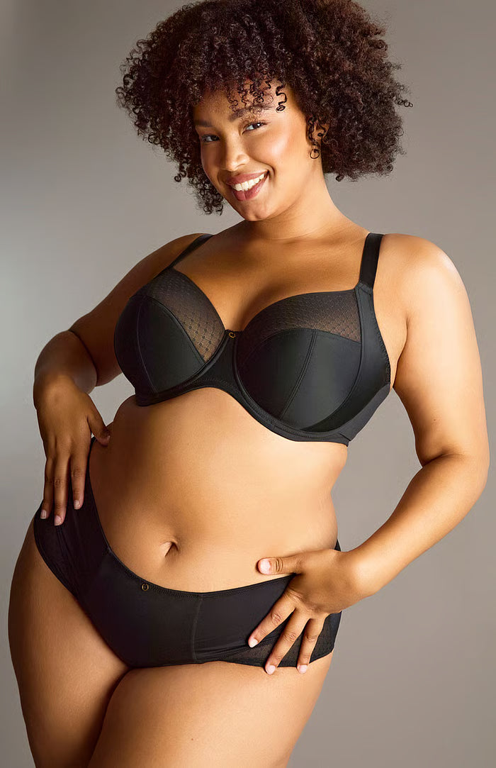 Woman wearing a black bra and panties set against a neutral background