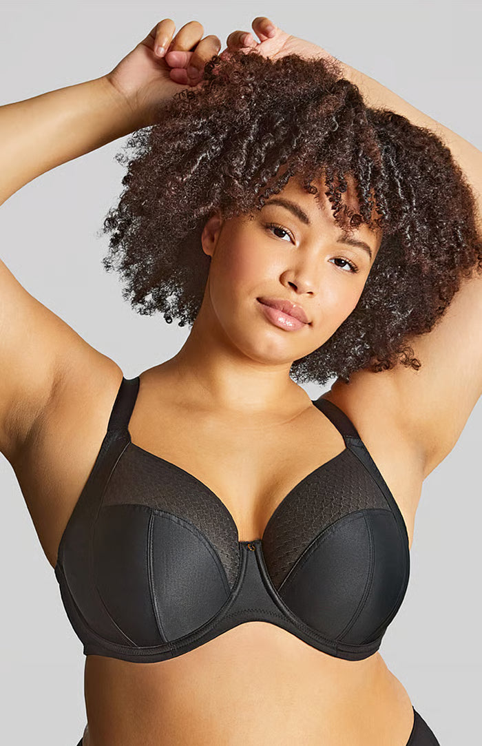 Woman wearing a black bra against a gray background