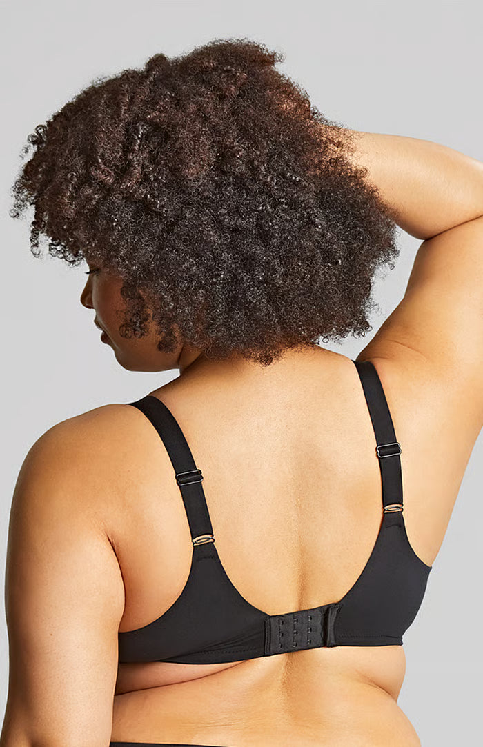 Woman wearing a black bra against a gray background