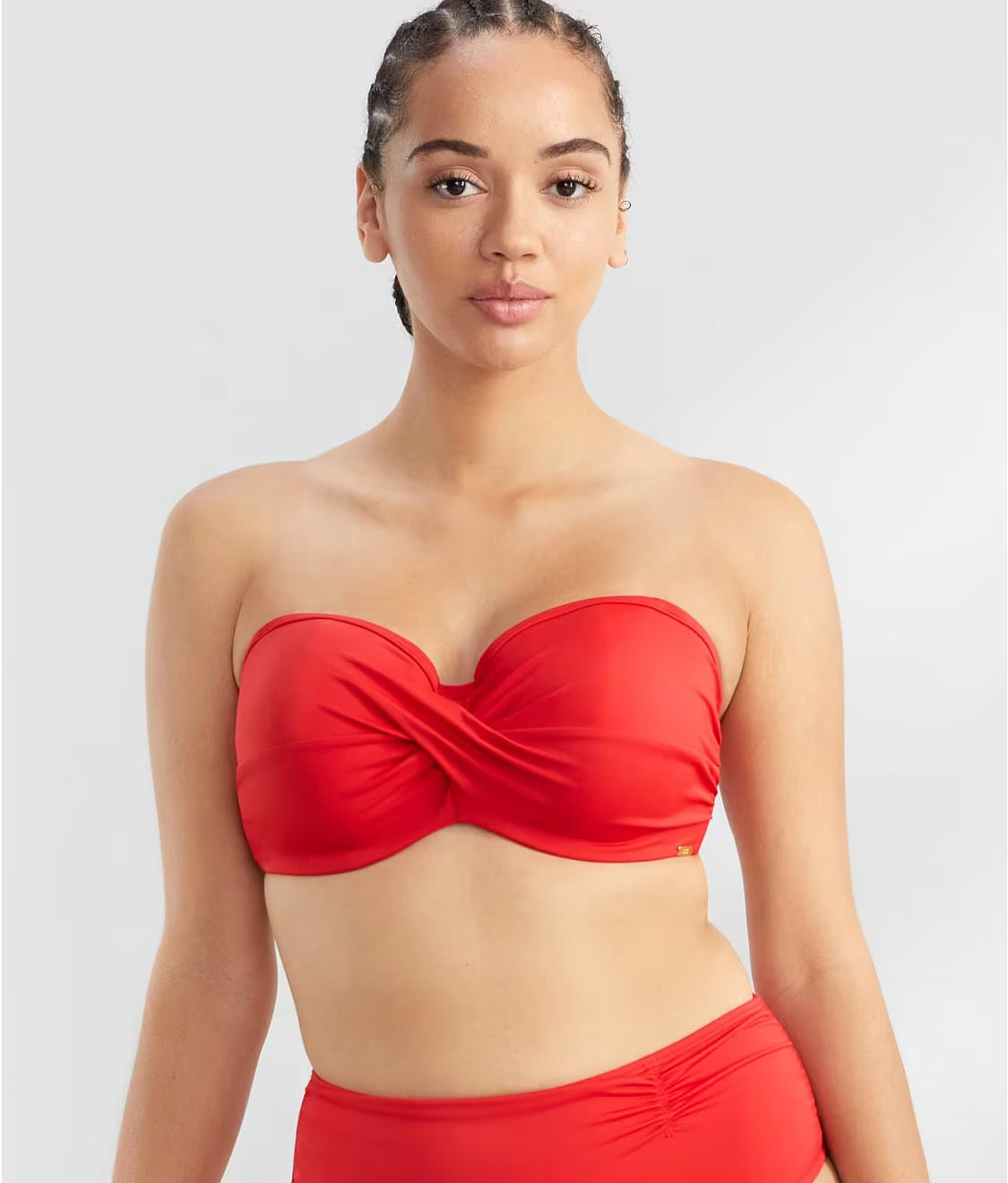 Woman wearing a red strapless bikini top on a white background