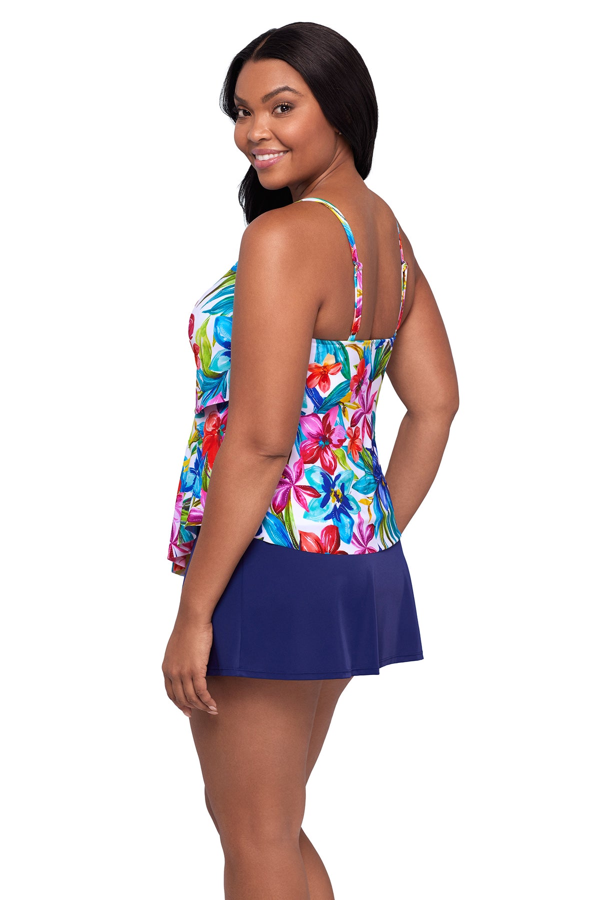 Woman wearing a colorful floral top and navy skirt on a white background